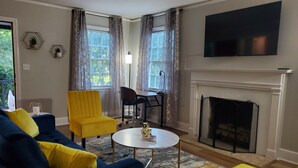 Ein Wohnzimmer mit blauem Sofa, gelbem Sessel und Kamin.