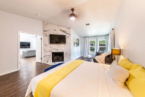 Een moderne hotelkamer met een groot bed, een open haard, een aan de muur bevestigde televisie en uitzicht op de omgeving.