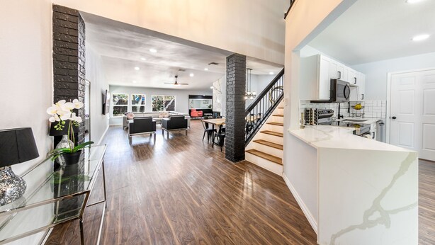 A spacious living area with a modern kitchen, a dining area, and a staircase leading to an upper level. - Elite Retreat w/ pool table & shuffleboard @ La Cantera, Six Flags, RIM, UTSA (San Antonio)