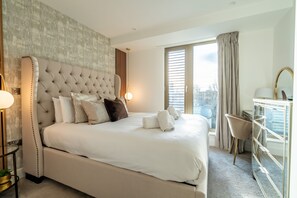 A modern hotel room with a large bed, a desk, and a view of the city. - Beautifully Furnished, Central, 2 Bedroom Apartment - With Parking (York)