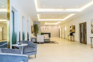 A spacious, modern lobby with a grey sofa, a round table, and a potted plant. - Beautifully Furnished, Central, 2 Bedroom Apartment - With Parking (York)