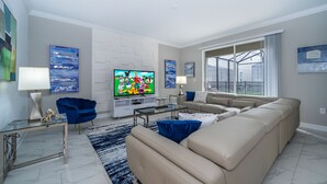 Ett modernt vardagsrum med en beige soffa, ett soffbord i glas och en platt-TV.
