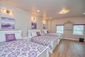 A bedroom with three beds, each with a patterned bedspread and matching pillows. There are wall-mounted light fixtures and a decorative headboard above the beds. - 5-Star Luxury Home Sleeps 22+ Airport proximity (Union City)