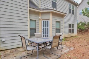 A patio with a table and four chairs, a door, and windows on a house. - 5-Star Luxury Home Sleeps 22+ Airport proximity (Union City)