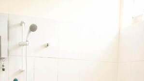 Een kleine, witte badkamer met toilet, douche en wastafel.