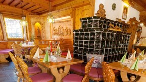 A wooden interior with tables and chairs, a decorative wall with reliefs, and a wine rack.