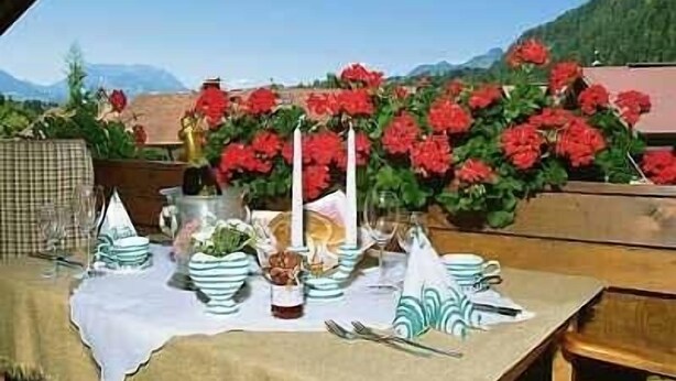 A table set outdoors with a view of mountains and red flowers in the background.