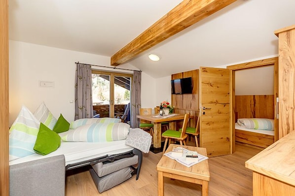 Une pièce de taille modeste comprenant un lit, une petite table, un téléviseur et une armoire en bois.
