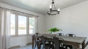 Un comedor con una mesa y sillas de madera, una planta en maceta y una ventana con cortinas.