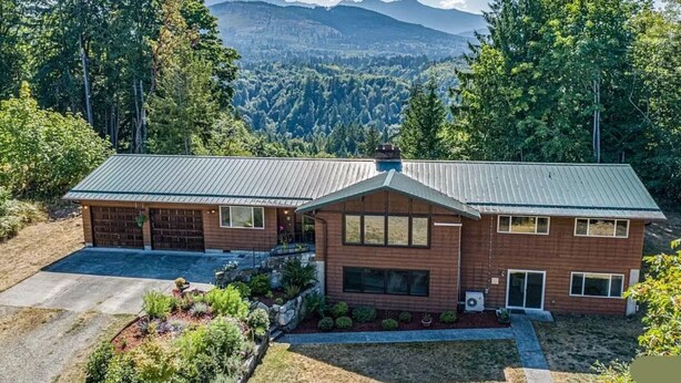 A two-story house with a metal roof, surrounded by a landscaped garden and forested hills. - Secluded Rural Retreat in the Olympic Foothills Near Olympic National Park (Port Angeles)