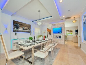 Una sala da pranzo moderna con tavolo in vetro, sedie trasparenti e un lampadario.