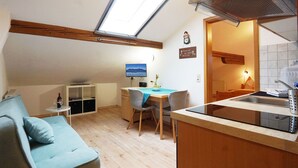 A compact living space with a kitchenette, a dining area, a sofa, and a TV. - Ferienwohnung III im 2. Stock mit Balkon, Wohnküche, Schlafzimmer, Dusche/wc, Balkon (Chieming)