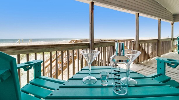 Eine Holzterrasse mit Blick auf Strand und Meer.