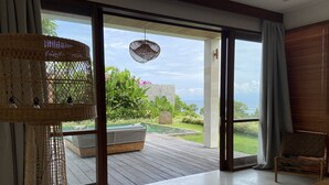 A spacious room with a large sliding glass door leading to an outdoor area with a pool and lush greenery. - Villa Biarritz (Pecatu)