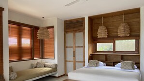 A bedroom with a large bed, a bench, a sofa, and a window with blinds. - Villa Biarritz (Pecatu)