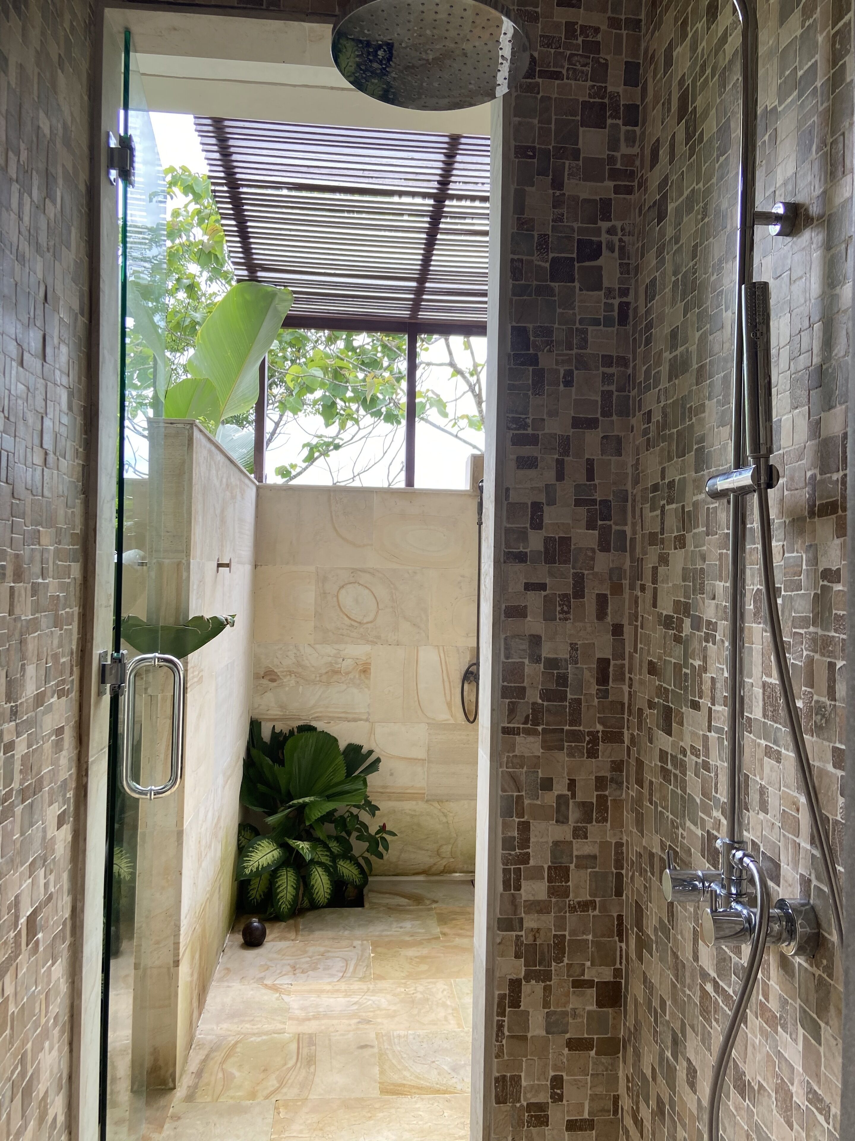A shower area with a tiled wall, a glass door, and a showerhead.