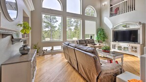 A spacious living room with a large sectional sofa, a fireplace, a television, and a balcony with a railing. - Estate w/ Indoor Pool & Decks ~ 25 Mi to Dtwn (Colorado Springs)