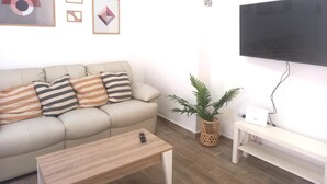 Una sala de estar moderna con un sofá, una mesa de centro, un televisor y elementos decorativos en la pared.