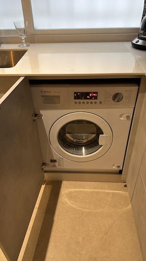 A Bosch washing machine in a compact, built-in cabinet with a control panel and a digital display.