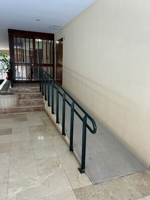 A staircase with a metal handrail, a door with a glass panel, and a potted plant.