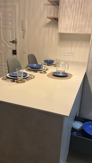 Et spiseområde med et hvidt bord, blå tallerkener og en klar kande.