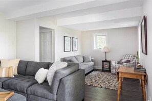 Una sala de estar con un sofá gris, un tapete estampado y una pequeña mesa de madera.