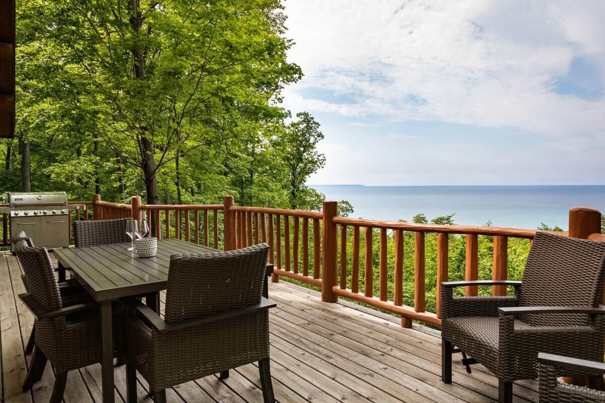 A wooden deck with a table and chairs, overlooking a body of water.