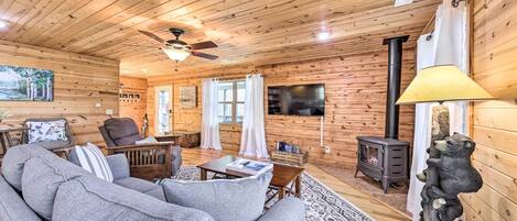 Een knus cabin interieur met een bank, houten plafond, open haard en een televisie.