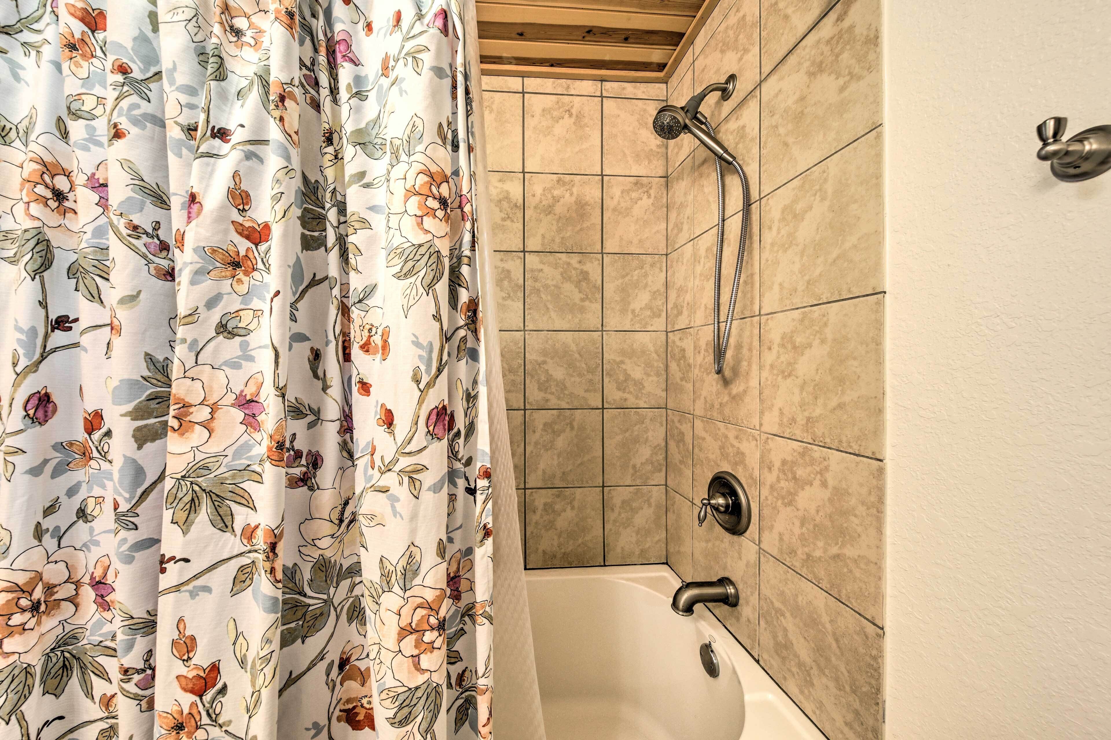 A bathroom with a bathtub, shower, and floral shower curtain.