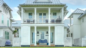 Een tweelaags huis met een veranda, een overdekte voordeur en een kleine voortuin.