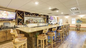 Een bar met een lange toonbank, verschillende krukken en een televisiescherm waarop een worstelwedstrijd te zien is.