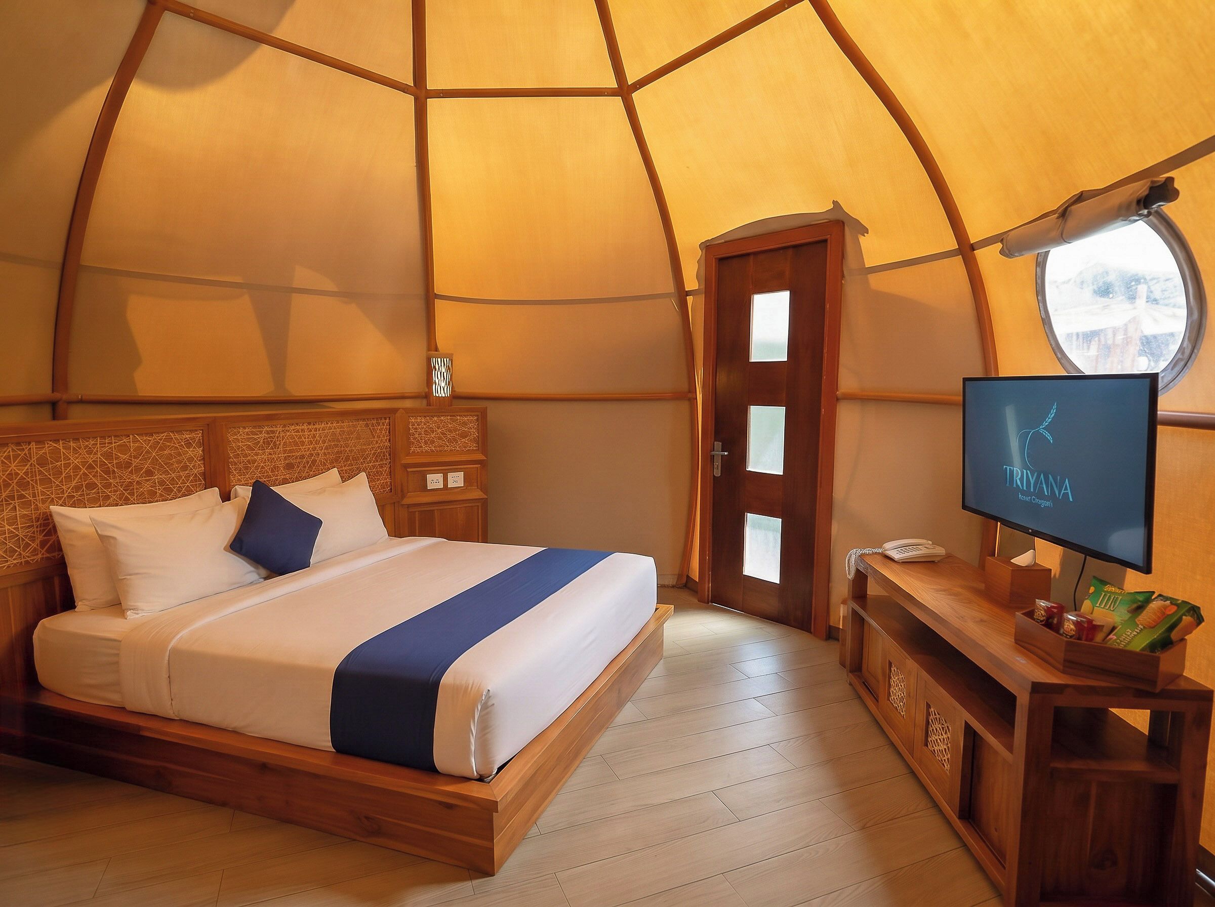 Um quarto com cama, televisão e porta.