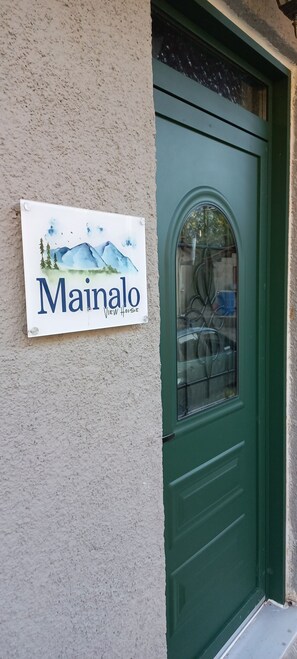 Una puerta verde con un panel de vidrio y un cartel que dice 'Mainalo View House'.
