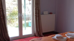 A bedroom with a bed, a radiator, a window with curtains, and a view of the outdoors. - Mainalo View House - A place for relaxing  (Vytina)