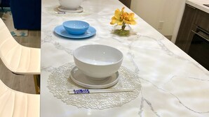 A modern kitchen with a marble countertop, a water dispenser, and a blue chair. - Discovery Bay-Resolution Ocean View Condo (Honolulu)