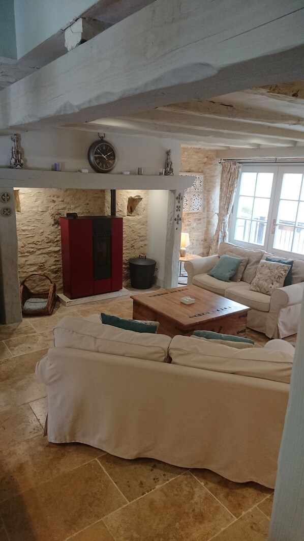 Un salon avec un mur en pierre, un meuble rouge, un canapé beige et une table basse en bois.