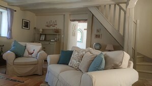Una sala de estar con dos sofás, una escalera y un comedor.