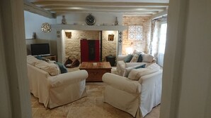 Una sala de estar acogedora con una pared de piedra, una chimenea y un televisor.