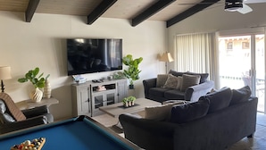 Ein Wohnzimmer mit Billardtisch, einer Couch, einem Fernseher und einem Deckenventilator.