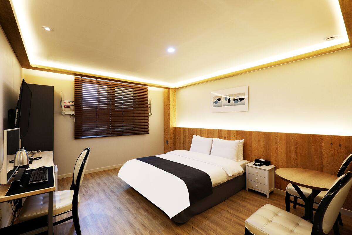 A hotel room with a bed, desk, chair, and a small table.