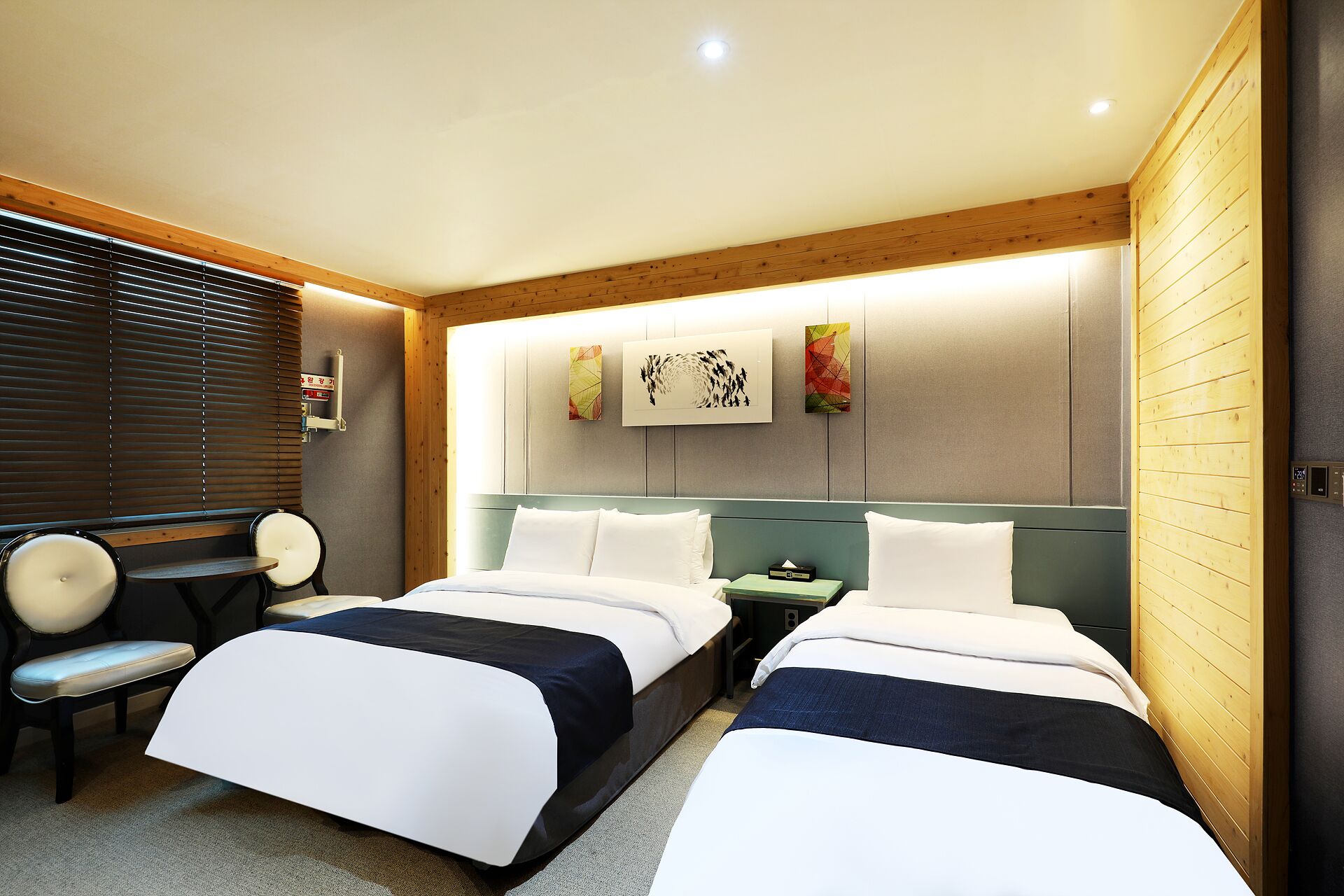 A hotel room with two beds, a desk, and a chair.