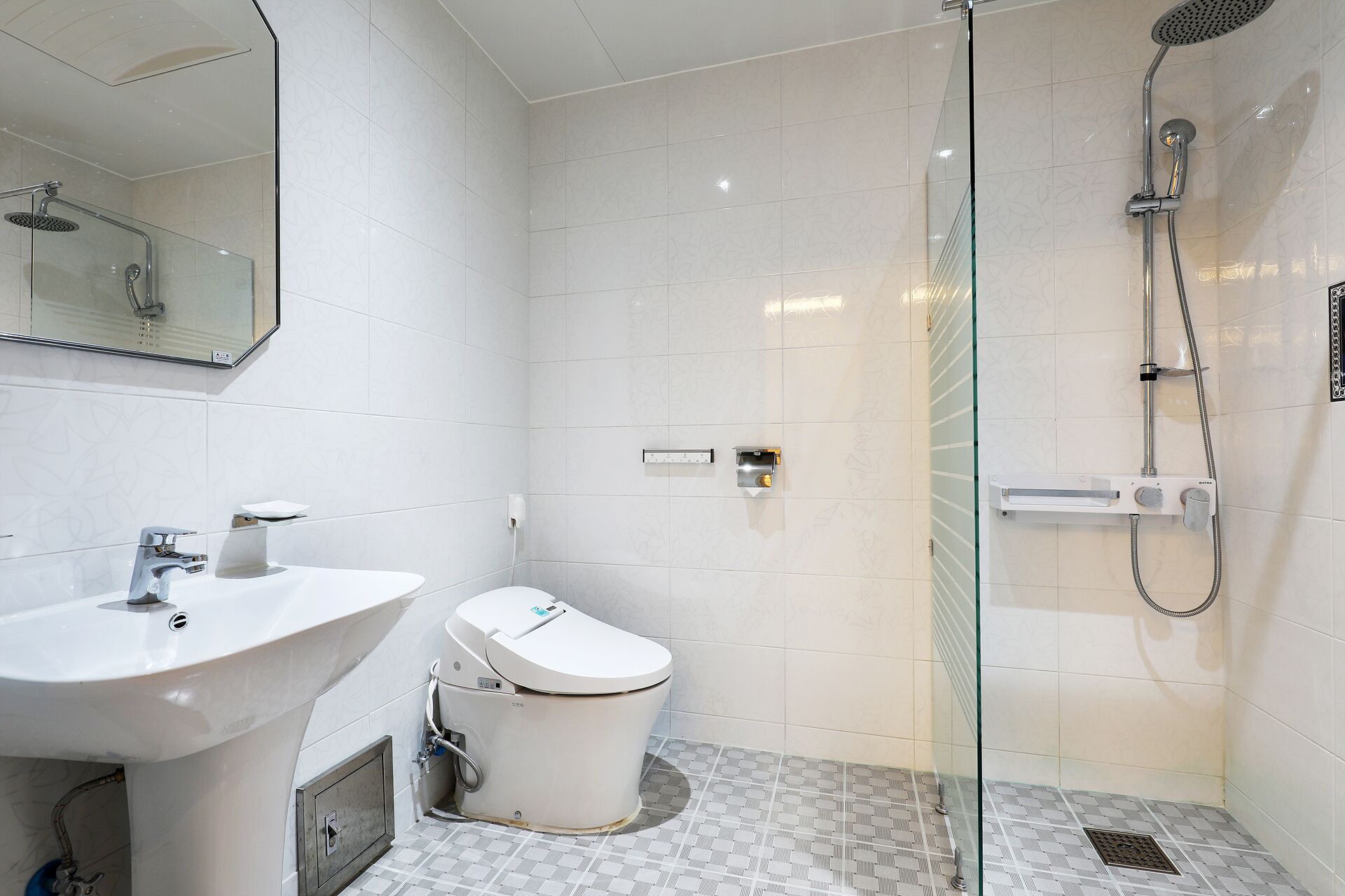 Un baño moderno con ducha acristalada, lavabo blanco y retrete.