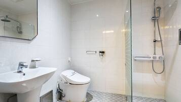 Un baño moderno con ducha acristalada, lavabo blanco y retrete.