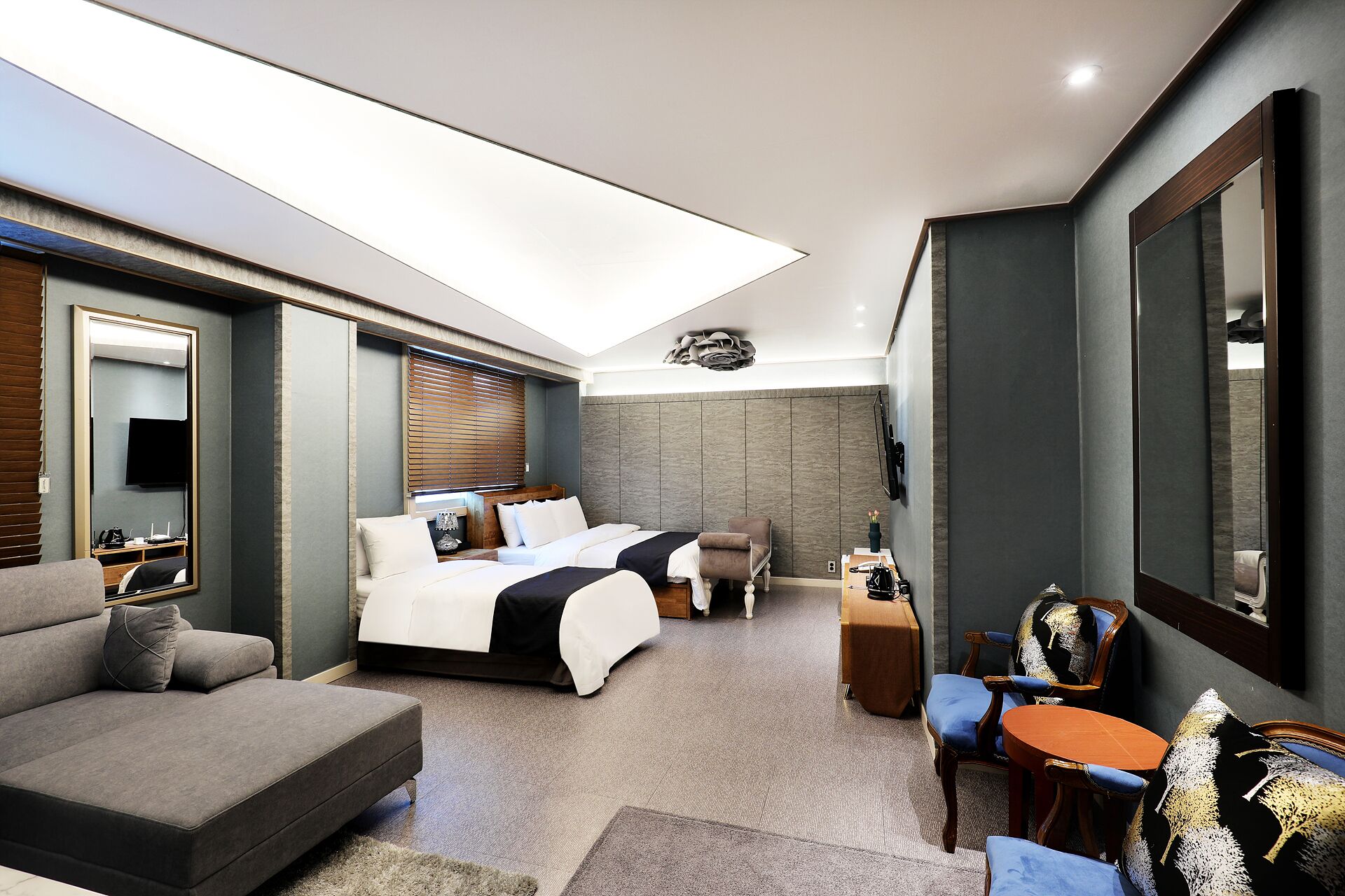 A modern hotel room with a large bed, a sofa, a desk, and a TV.