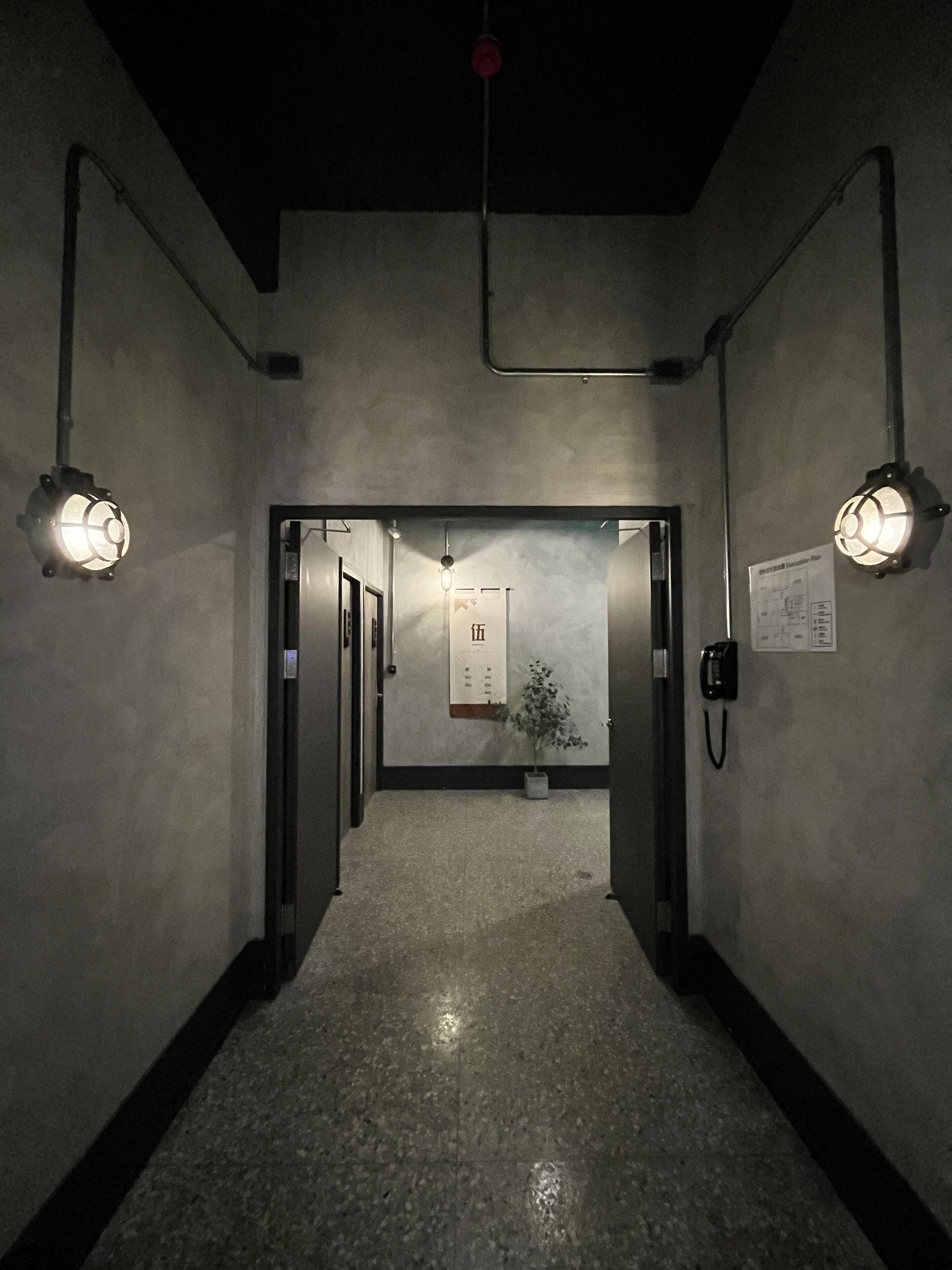 Un corridoio con pavimento bagnato, una pianta e un avviso appeso al muro.