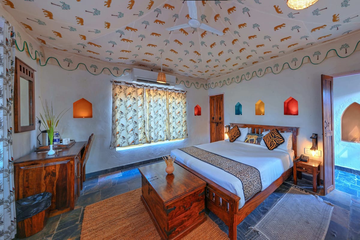 Une chambre à coucher avec un lit, des meubles en bois, des rideaux à motifs et des appliques murales décoratives.