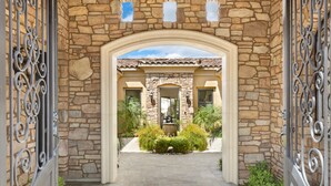 Un arco de piedra que conduce a una casa con techo de tejas y fachada de piedra.
