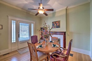 A dining room with a wooden table set for four, surrounded by leather chairs. A ceiling fan is above the table, and there is a vase with flowers on the table. - Louisville Home w/ Hot Tub in The Highlands! (Louisville)