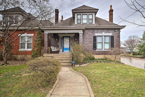 A two-story house with a front porch, a blue door, and a brick exterior. - Louisville Home w/ Hot Tub in The Highlands! (Louisville)