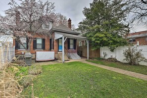 A brick house with a covered patio, a small front yard, and a wooden fence. - Louisville Home w/ Hot Tub in The Highlands! (Louisville)